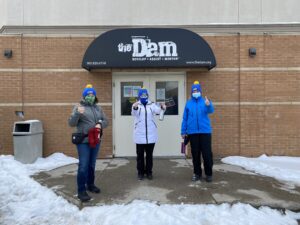 Three people stand at the front door of a dropin centre